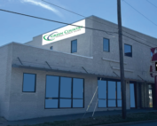 15th → Green Country Federal Credit Union Exterior view of a brick commercial building with large storefront windows and a street sign reading Green County against a blue sky